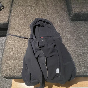 Berkeley zip up  - Säljer en svart fleecejacka med huva från Tradesnip. Jackan har dragkedja framtill och broderad logga på ryggen. Perfekt för kyliga dagar.