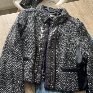 Mönstrad jacka från Oui Collection - Snygg jacka från Oui Collection i ett mönstrat tyg med inslag av blått och beige. Jackan har långa ärmar och dekorativa detaljer längs med dragkedjan. Perfekt för att ge din outfit en stilfull touch.