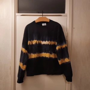 Svart tröja - Säljer enl svart tröja med tiedye/batikmönster design från Jack & Jones.. Tröjan har långa ärmar och en rund halsringning. Perfekt för en avslappnad stil. Något nopprig, därav det låga priset. St s. 