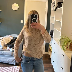 Beige spetsmönstrad tröja från H&M - Säljer en beige tröja med långa ärmar från H&M med ett vackert spetsmönster. Säljer då den inte har kommit till användning. (Har själv satt dit klämman).❤️