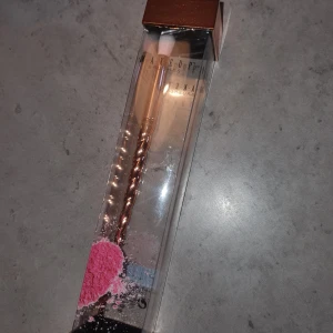 Sminkborste  - Snygg sminkborste med rosa borst och ett vridet handtag i roséguld. 