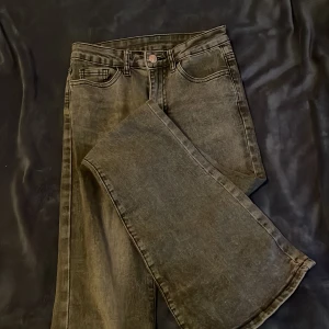 mörk gråa jeansbyxor - Snygga svart/gråa jeansbyxor med en klassisk design. De har en rak passform och är perfekta för en stilren look. Byxorna har fem fickor och en knappgylf.