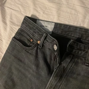Svarta loose fit jeans - Säljer ett par svarta loose fit jeans med klassisk femficksdesign. De har en dragkedja och knapp framtill. Perfekta för en avslappnad stil.
