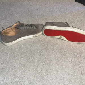 Äkta loubitins - Snygga grå sneakers med den ikoniska röda sulan 🔴. Skorna har snörning och är tillverkade i mocka med sofistikerad look☕️🧐. Medföljer endast skor därav det låga👟. Det finns extremt små defekter på skorna skriv för bilder💬! Riktigt fräscha går att tvättas för ännu fräschare look😎. Priset är inte hugget i sten 🪨!!