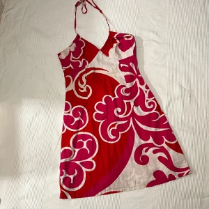 Sommrig halterneckklänning - Snygg röd, rosa och vit klänning från H&M med ett fint mönster. Klänningen knyts i nacken och sitter väldigt bekvämt! Perfekt för sommaren🌸