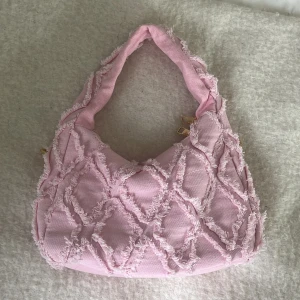 Rosa axelväska med fransar - Säljer en söt rosa axelväska med unikt fransmönster. Väskan har en mjuk och quiltad design. Jätte bra storlek och snygg jeans aktigt material. 