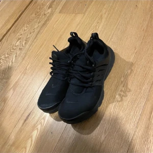 Svarta sneakers från Nike - Snygga svarta sneakers från Nike med snörning och en stilren design. Perfekta för en casual look och bekväma att bära hela dagen.