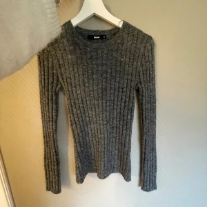 Grå ribbad tröja från BikBok - Säljer en stilren grå ribbad tröja från BikBok i storlek XS. Tröjan har en klassisk design med långa ärmar och en bekväm passform. Endast testat men hunnit ta bort lappen tyvärr. Använd gärna köp nu🌸