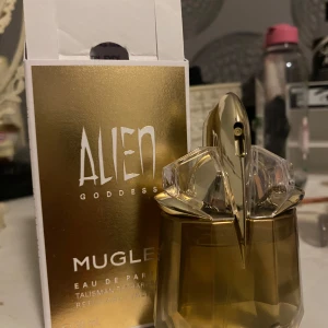 Alien Goddess Eau de Parfum från Mugler - Alien Goddess Eau de Parfum från Mugler i en elegant flaska med guld- och kristalldetaljer. Parfymen är på 30 ml och har en påfyllningsbar design. Förpackningen är i guld och vitt, vilket ger en lyxig känsla. Original pris ligger på 995 kr på kicks.