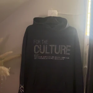 Mörkblå hoodie med glitter text  - Snygg mörkblå hoodie med texten 'FOR THE CULTURE' i glittriga bokstäver. En unik broderad detalj på ärmen. 