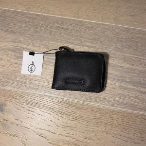 Svart plånbok från Stradivarius - Svart plånbok från Stradivarius med dragkedja. Perfekt för att hålla ordning på kort och kontanter. Kompakt design som passar i de flesta väskor.