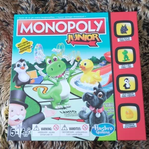 Monopoly Junior - Monopoly Junior är en barnvänlig version av det klassiska brädspelet. Perfekt för yngre spelare, med roliga spelpjäser som en dinosaurie och en pingvin. Spelet lär barn att hantera pengar och fastigheter på ett enkelt och underhållande sätt. Passar för barn från 5 år och uppåt. Spel beskrivning finns på Svenska och Finska tror jag!