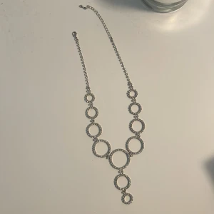 Silverfärgat halsband med cirkeldetaljer - Elegant halsband i silverfärg med flera sammanlänkade cirklar. Perfekt för att ge en stilren touch till din outfit. Justerbar kedja för optimal passform.