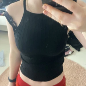 Svart ribbad topp - Snygg svart ribbad topp. Toppen är ärmlös och har en tight passform som framhäver figuren. Perfekt för en stilren look.