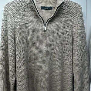 Beige stickad tröja från Dressmann - Säljer en snygg beige stickad tröja från Dressmann i storlek S. Tröjan har en dragkedja vid halsen och långa ärmar, perfekt för kyliga dagar. Den är i mycket bra skick och passar både till vardags och lite finare tillfällen.