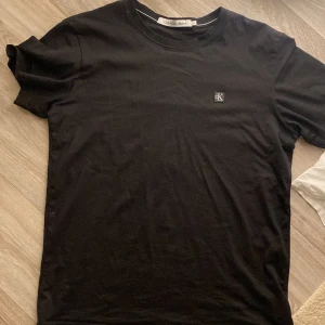 Svart t-shirt från Calvin Klein Jeans - Säljer en stilren svart t-shirt från Calvin Klein Jeans i storlek M. Den har en liten CK-logga på bröstet och är gjord i mjukt bomullsmaterial. Perfekt för vardagsbruk eller en avslappnad kväll ute. Passar till allt!