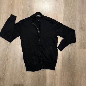 Mörkblå/ Svart Zip Up från Dressmann - Säljer en stilren svart/ mörkblå kofta från Dressmann i storlek M. Den är gjord av mjuk bomull och har en praktisk dragkedja framtill. Perfekt för både vardag och lite finare tillfällen. Passar bra till höst och vår! Använd endast några enstaka gånger