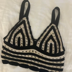 Svart och beige virkad topp - Snygg svart och beige virkad topp med ett unikt mönster. Toppen har breda axelband och en croppad passform, perfekt för sommarens alla festivaler eller en dag på stranden eller under en varm kofta under vinterhalvåret. 