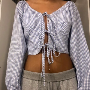 Blåvit rutig offshoulder-top -  offshoulder-top med långa ärmar och knytning framtill.