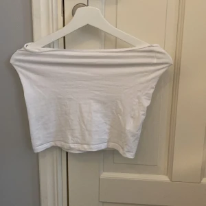 Vit offshoulder topp från H&M - Säljer en stilren vit offshoulder topp från H&M i storlek M. Perfekt för sommardagar eller en avslappnad kvällslook. Toppen är i bra skick och har en croppad passform som ger en trendig touch.