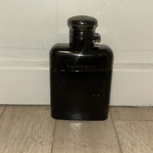 Svart parfymflaska från Ralph Lauren  - •	Toppnoter: Frisk citrus och kryddig ingefära ger en energisk start. 	•	Hjärtnoter: En sofistikerad mix av lavendel och jasmin skapar en tidlös elegans. 	•	Basnoter: Varmt trä och musk ger en långvarig och minnesvärd. jag tar även emot byten. Varan kosta 1150kr ny