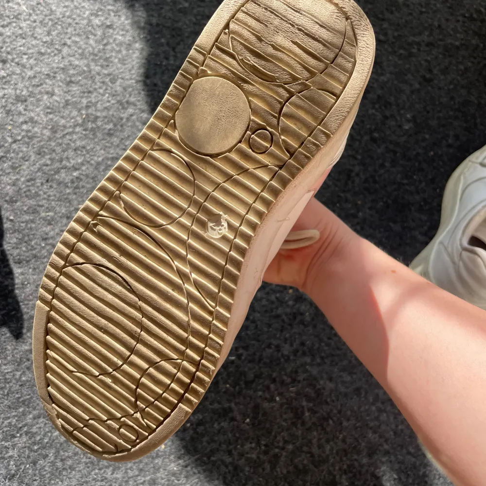 Säljer ett par vita sneakers med rosa detaljer från NLY Shoes i storlek EU 37. Skorna har snörning och är i acceptabelt skick med lite slitage på insidan. Perfekta för vardagsbruk och ger en söt touch till din outfit!. Skor.