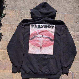 Svart hoodie från Playboy x Missguided - Säljer en svart hoodie från Playboy x Missguided. Den har en stor tryck med läppar och text på baksidan och en liten Playboy-logga i rött på framsidan. Perfekt för en avslappnad stil. Den är i bra skick och superbekväm!       Storlek XL