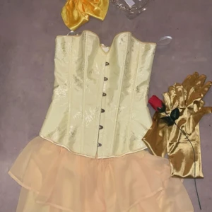 Gul korsettklänning med tyllkjol - Säljer en superfin gul korsettklänning med en fluffig tyllkjol. Klänningen har en snygg snörning framtill och är perfekt för festliga tillfällen. Den är axelbandslös och ger en elegant look. Perfekt för dig som vill sticka ut!