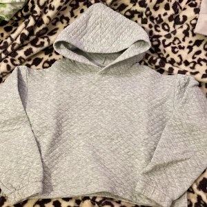 Grå quiltad hoodie från Kappahl - Mysig grå hoodie från Kappahl i storlek 146/152. Den är quiltad och perfekt för kyliga dagar. Hoodien har en bekväm passform med långa ärmar och en stor huva. Perfekt för att hålla sig varm och stilren samtidigt! 🐾