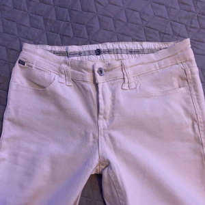 Beige/vita jeans - Lågmidjade, slit på utsidan av benen längst ner, knappast använda, märket är Rinascimento (italienskt), coola fickor, ner till golvet på mig som är ca 170cm. Står inte vilken storlek dem är men skulle säga XS/S men lutar mer mot XS💞
