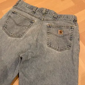 Säljer ett par klassiska blå jeans från Carhartt. De har en loose passform och är i bra skick med några små fläckar. Perfekta för en avslappnad stil. Jeansmaterialet är slitstarkt och har en vintage look.                    Jag kan gå ner i pris vid snabb affär.