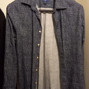 Grå skjorta från GANT - Säljer en stilren grå skjorta från GANT i storlek M. Skjortan har en klassisk krage och knappar framtill. Perfekt för både vardag och festliga tillfällen. Materialet känns mjukt och bekvämt, vilket gör den idealisk för höst och vinter.