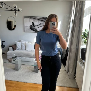 Blå t-shirt - Säljer en enkel och stilren blå t-shirt i mjukt material. Perfekt för vardagsbruk och kan enkelt matchas med jeans eller kjol. T-shirten har en normal passform och korta ärmar.