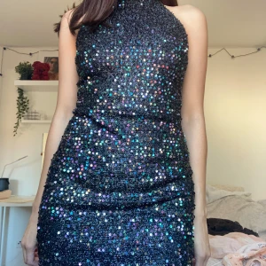 Svart glittrig klänning - Snygg svart klänning med massor av glittriga paljetter som verkligen fångar ljuset. Perfekt för en festkväll! Den är ärmlös och har en tight passform som framhäver figuren. Klänningen är i mycket bra skick och redo för att användas på nästa stora event.