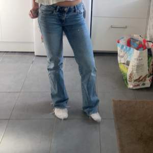 Säljer ett par snygga blå bootcut jeans i bra skick. De är lågmidjade och har en klassisk femficksdesign. Perfekta för en avslappnad vardagslook eller en utekväll. Passar bra med sneakers eller klackar!