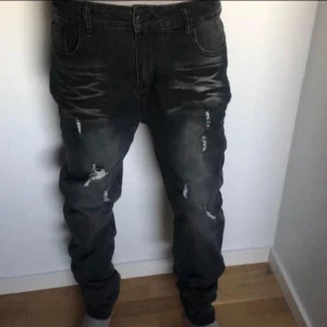 Svarta jeans med slitningar - Säljer ett par svarta jeans i bra skick med coola slitningar på framsidan. De har en slim passform och är perfekta för en avslappnad stil. Jeansen är midwaist och har en klassisk femficksdesign. Perfekta för både vardag och fest!