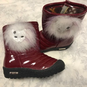 Vinröda vinterstövlar med pälsdetalj - Säljer ett par unika vinröda vinterstövlar med quiltad design och fluffig pälsdetalj. De har en robust svart sula och är fodrade för extra värme. Perfekta för kalla vinterdagar när du vill sticka ut lite extra!  Stlk kvar 27,28,30.                                   Med fleece inuti , rekommenderar att välja en stlk större 