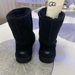Svarta UGG boots - Säljer ett par klassiska svarta UGG boots i mycket bra skick med en mjuk insida som håller fötterna varma. Perfekta för kalla vinterdagar. Sulan är robust och ger bra grepp. Dom är köpta för originalpriset vilket är ca 2600kr, fick dom som present, dom är oanvända då dom inte passar mig, passar strlk 40-41💞💞