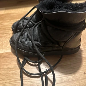 Svarta boots med foder - Säljer ett par svarta boots från Inuikii i skinn med mjukt foder. Perfekta för vintern med sin varma insida och robusta snörning. De har en stilren design och är väl använda. Passar perfekt för kalla dagar!
