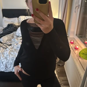 Svart långärmad tröja med detalj - Säljer en svart långärmad tröja med en cool randig detalj vid halsen. Perfekt för höst och vinter, den är både stilren och bekväm. Passar bra till både vardag och fest. Hör av dig vid intresse!