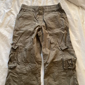 Gröna cargos - Säljer ett par snygga gröna cargobyxor från Gina Tricot. De har flera praktiska fickor och en elastisk midja för extra komfort. Perfekta för en avslappnad stil eller äventyr utomhus. Passar bra till både vardag och utflykter. Aldrig använt💕 nypris 700