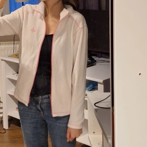 Vit fleecejacka med rosa detaljer - Säljer en supermysig vit fleecejacka med rosa detaljer. Den är i storlek 152.