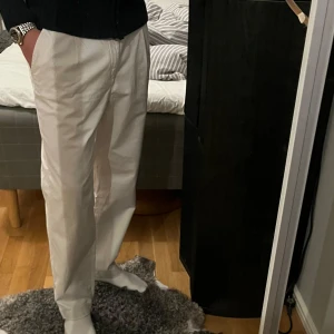 Vita kostymbyxor - Säljer ett par stilrena vita kostymbyxor i mycket bra skick. De har en klassisk straight passform och är perfekta för både formella och semi-formella tillfällen. Byxorna har en midwaist design och är tillverkade i ett bekvämt material som ger en snygg siluett.
