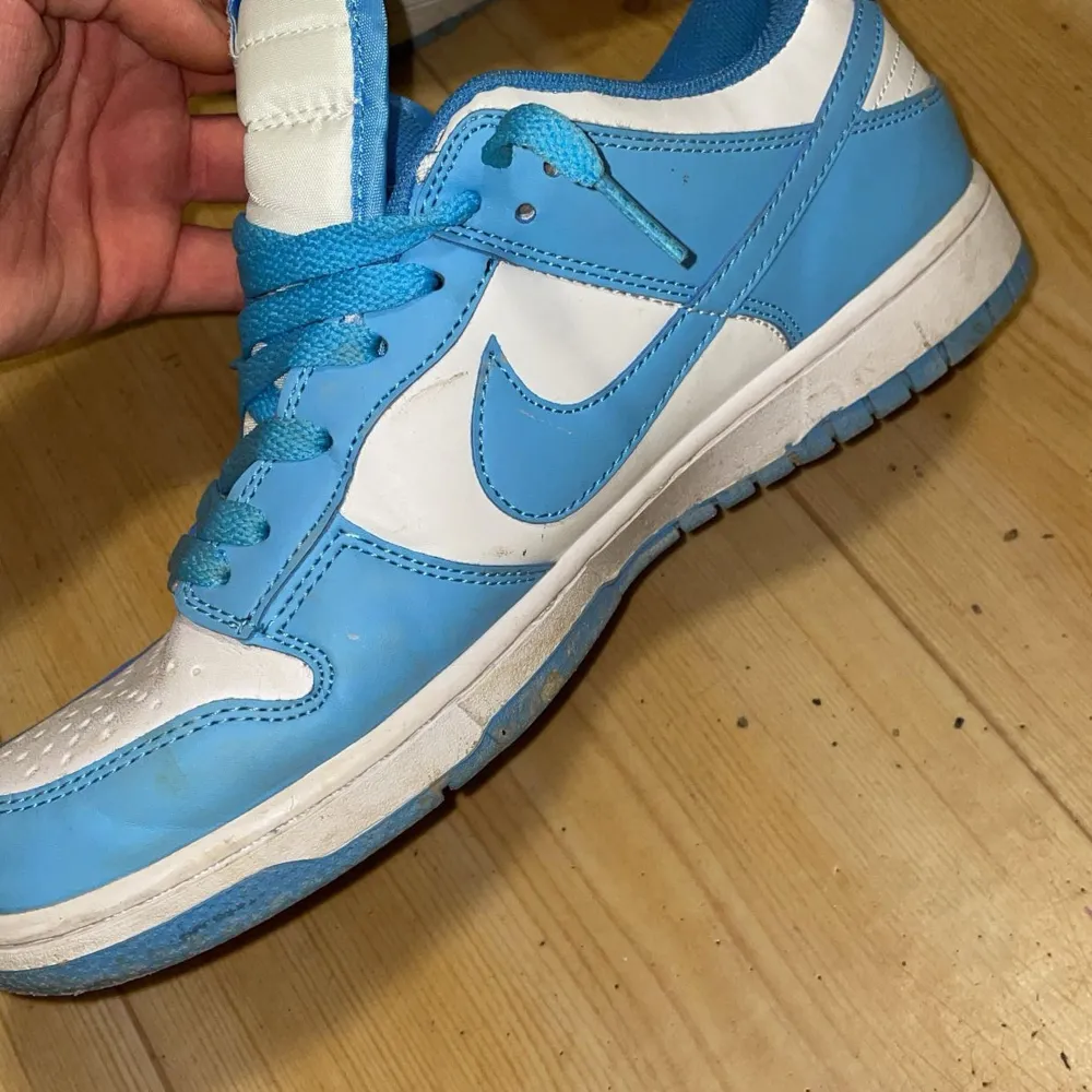 Säljer ett par Nike Dunk sneakers i blått och vitt. De har en klassisk design med snörning och en bekväm passform. Skorna är i bra skick med lite slitage på sulan. Perfekta för både vardag och träning! Ska såklart rengöras . Skor.