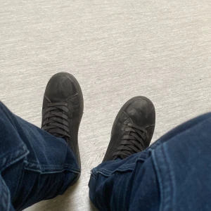 Svarta sneakers i mocka - Säljer ett par svarta sneakers i skinn. De har en klassisk design med snörning och är i bra skick. Perfekta för vardagsbruk och passar till det mesta i garderoben. Skostorlek 40.jag kan diskutera om priset och om köparen ska köpa så tvättar jag skorna och gör dom fräscha