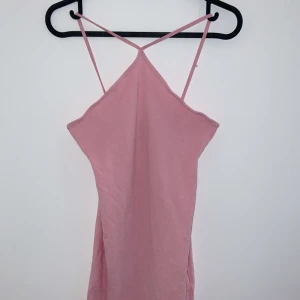 Rosa axelbandslös klänning - Söt rosa klänning med smala axelband och en enkel design. Perfekt för sommardagar eller en avslappnad fest. Klänningen har en mjuk och bekväm passform.