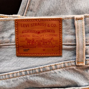 Levi's 501 ljusblå jeans - Säljer ett par klassiska Levi's 501 jeans i ljusblå färg. De är högmidjade med en straight passform, perfekt för både vardag och fest. Storlek w26 L28 Jeansen är i mycket bra skick och har den ikoniska läderpatchen baktill. Passar perfekt till en croppad topp eller en oversized tröja.