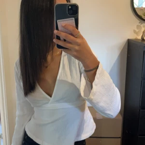 Vit omlottopp - Säljer en superfin vit omlottopp med långa ärmar. Toppen har en v-ringad design och är perfekt för både vardag och fest. Den är i ett mjukt och bekvämt material som sitter snyggt på kroppen. Den har en knytning i ryggen och är från Gina i storlek xxs ❤️