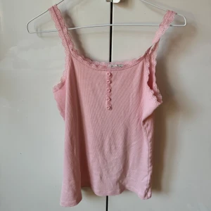 Rosa ribbad linnetopp från Tex Leone - Söt rosa ribbad linnetopp från Tex Leone i storlek M. Toppen har spetsdetaljer vid axelband och halsringning samt små knappar framtill. Passar även S!