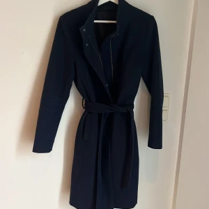 Marinblå kappa  - Snygg marinblå kappa i mycket bra skick.  Perfekt för höst och vår, Kappan har även en dragkedja framtill